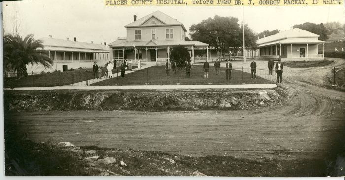 People gathered on the lawn of a small hospital complex, with labeling text reading Placer County hospital before 1920