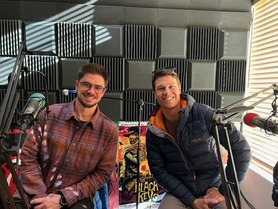 Ryan Murray (left) and Nick Martin (right) sit on stools behind mics at KTKE radio station and smile for a photo. 