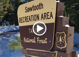 A brown and yellow Tahoe National Forest sign noting the entrance to Lower Sawtooth Recreation Area and a play button.
