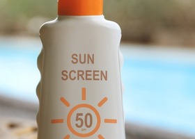 Bottle of sun screen protector with pool in the background