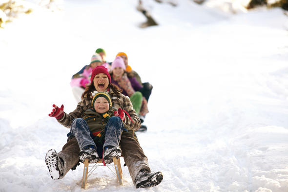 Mother and son on a sled, sledding down a snowy background