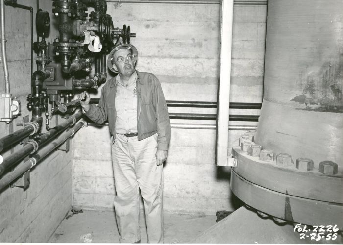 A man in a hard hat closes a pipe valve inside Folsom Dam