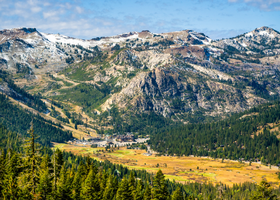 Mountain valley surrounded by pine trees and mountains in the background