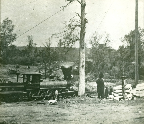 Four men stand alongside a steam engine train
