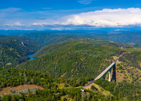 Aerial view of tree-covered foothills and a bridge