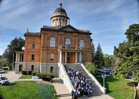 People in blue standing in front of Auburn Courthouse with blue pinwheels