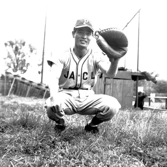 Bob Hayashida of the Placer Japanese American Citizens League Baseball team kneeling with his glove, his uniform marked “JACL.”