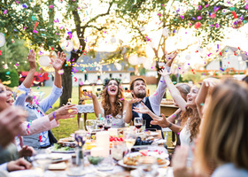 People celebrating at a table with food and throwing confetti
