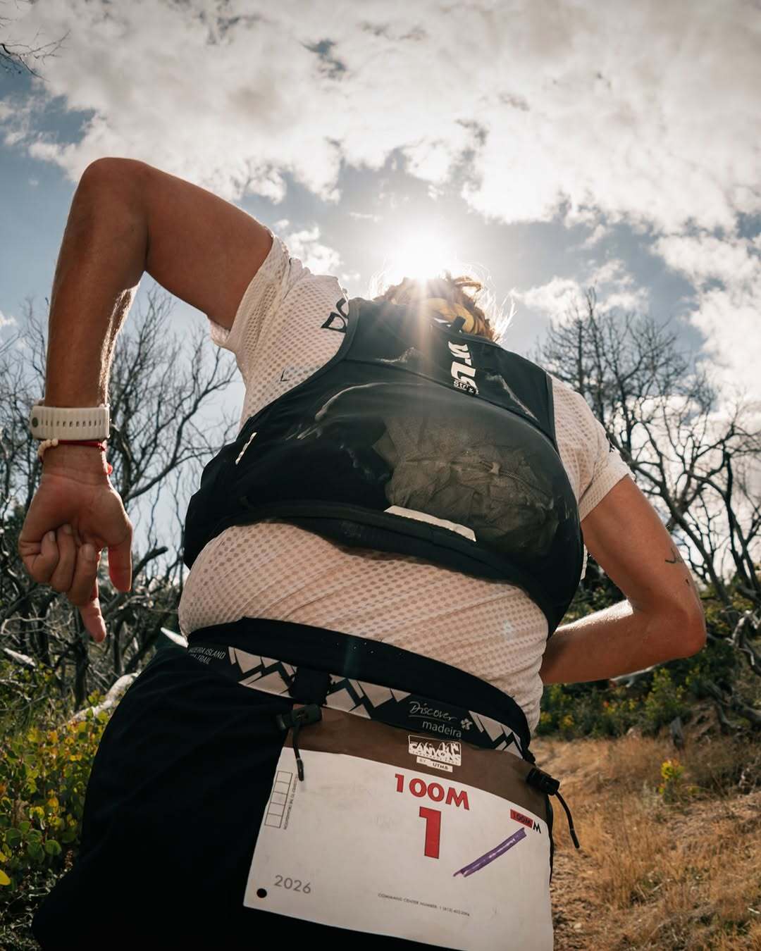 low angle shot of a runner running uphill, text: 100M 1