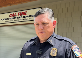 A CAL FIRE/Placer Fire Department unit forester in uniform outside a building w the dept sign  "Cooperative Fire Protection Since 1952"