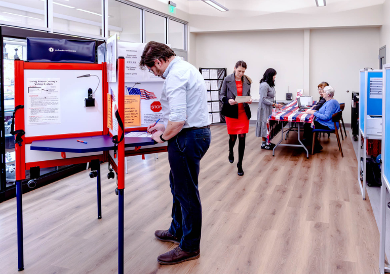 Man actively voting, 2 women in varying states of readying to vote