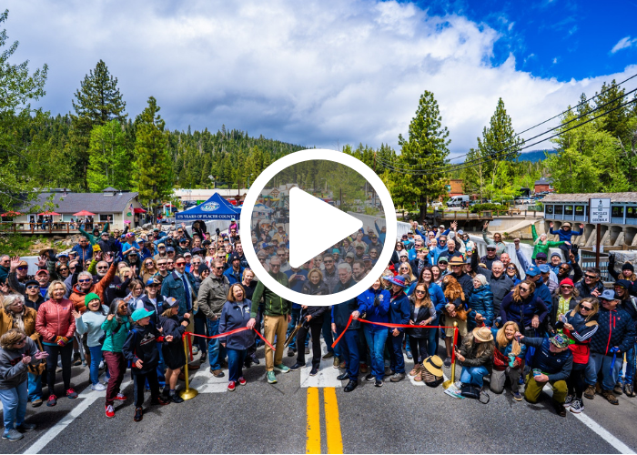 Crowd on Fanny Bridge in Tahoe City, cheering Supervisor Gustafson cuts a ribbon to celebrate the bridge opening with play button overlayed