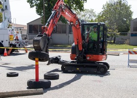 An equipment operator lifts a tire onto a cone