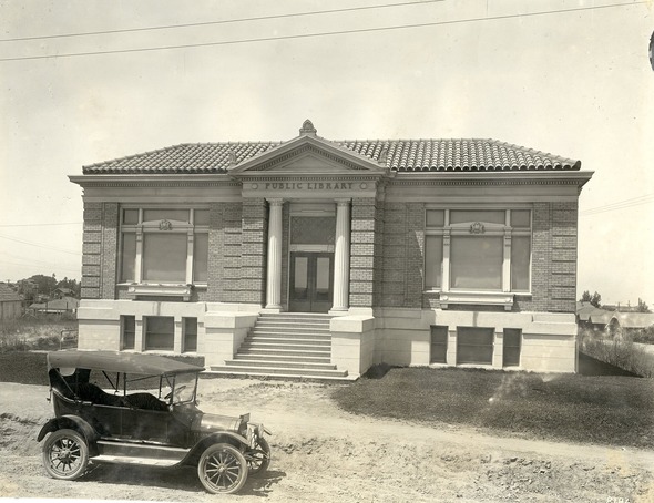 Historic photo of a public library building and a model-t car parked in the front.