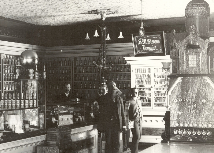 Historic photo of three men standing at the counter of a general store.