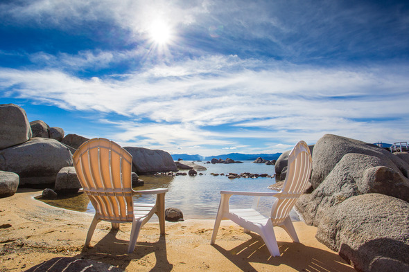 two beach chairs on a beach shore with big boulders