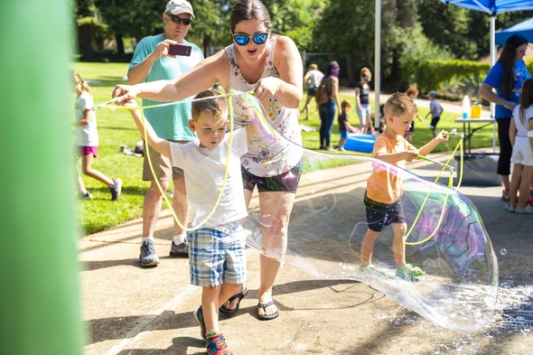 a mom and her kid playing with big bubble makers