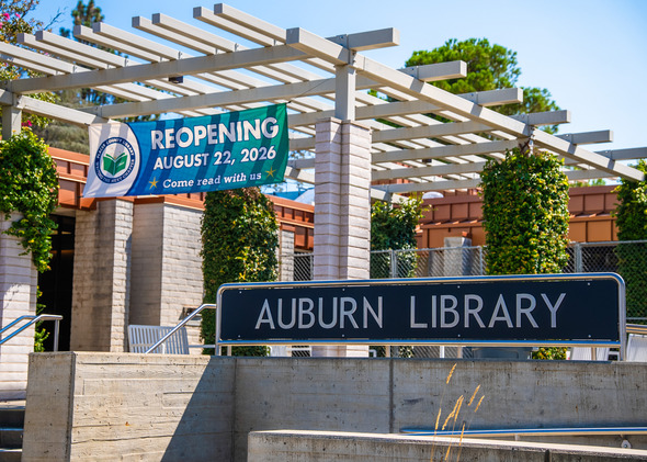 Exterior photo of the Auburn Library with a banner saying Reopening Aug. 22