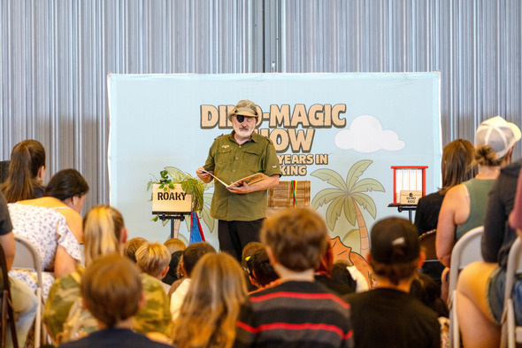 Man in safari outfit and eye patch reads to children at a Jurassic Summer Reading event