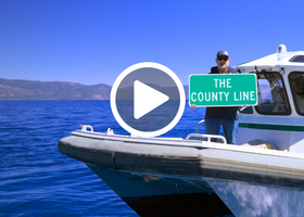 CEO Daniel Chatigny stands on the bow of the Sheriff’s Patrol boat, while holding “The County Line” sign