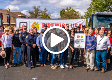 County and fire officials pose with neighbors in front of a South Placer Fire District fire engine and with a Firewise community commemorative sign