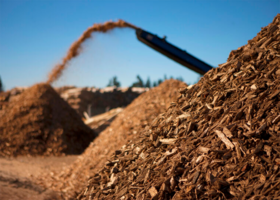 Wood chip pile in front of a conveyor belt machine distributing wood chips at the Eastern Placer Regional Landfill on a sunny day.