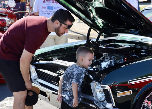 A man and child look at a car engine