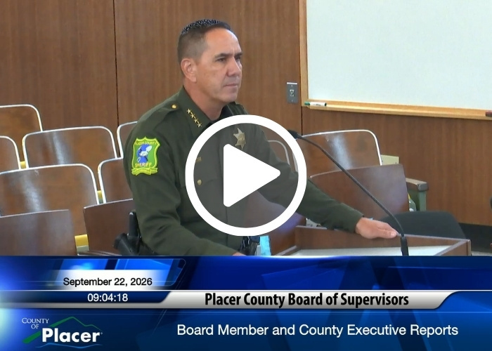 Placer County Sheriff Wayne Woo addresses the Placer County Board of Supervisors from a podium with a play button overlayed