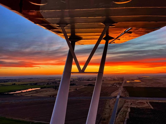 Aerial image over Lincoln from a plane with view of the wing and a red and orange sunset.