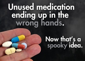 A close-up of a hand holding several colorful pills and tablets.