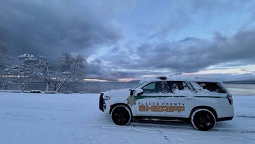 A PCSO patrol vehicle covered in snow in front of Lake Tahoe.