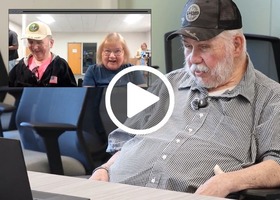 Video thumbnail showing an older adult seated at a table looking at a laptop.