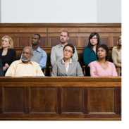A diverse group of jurors sit in a jury box and listen to arguments in an ongoing case.