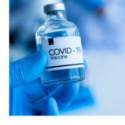 A gloved hand holds a vial of COVID-19 vaccine.
