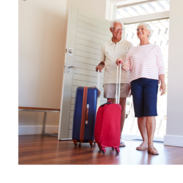 A man and a woman roll their luggage into a vacation home.