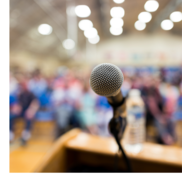 A microphone at a dais in front of a large group of people.