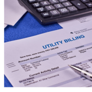 A pen and a calculator lay on top of a utility bill statement.