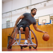A man in a wheelchair dribbles a basketball.
