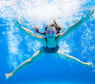 Little girl with red hair jumping into a pool