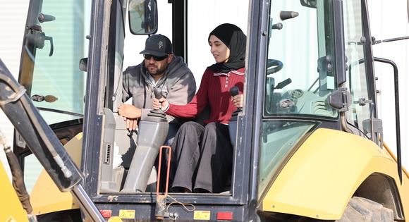 Photo of an EU employee and a student sitting in a backhoe vehicle