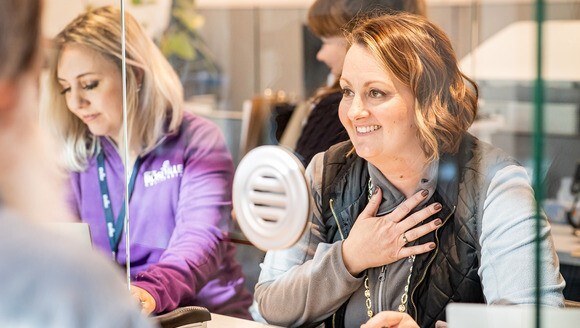 Photo of a woman smiling behind a customer service desk window