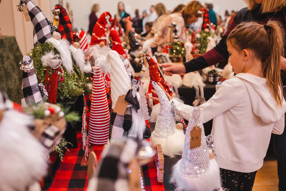 A child visits a table full of gnomes at a craft fair.