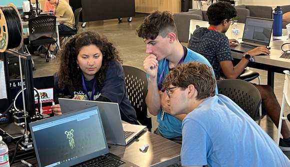Students at a table looking at a laptop during CAD class