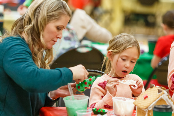 Photo of a mother and a daughter completing holiday crafts at a table
