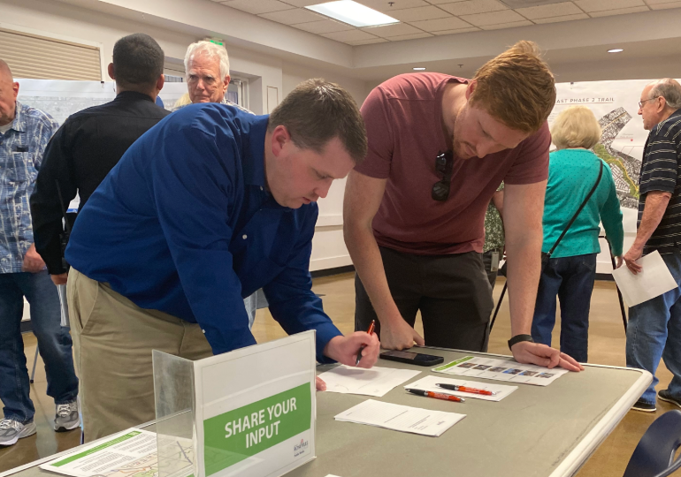 Photo of two people filling out feedback forms at an informational booth