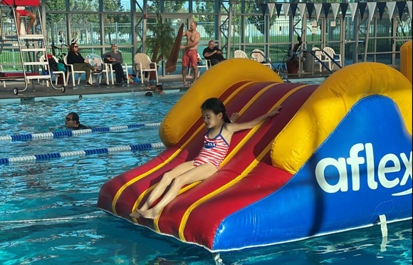 Photo of a young girl sliding down an inflatable slide at Mike Shellito Indoor Pool