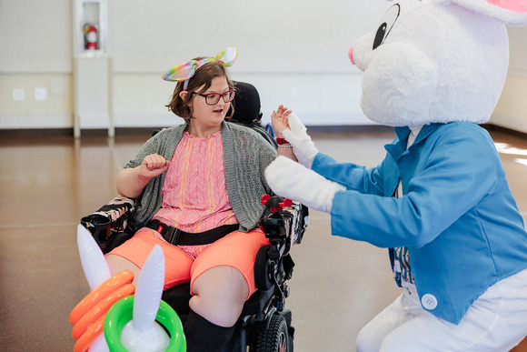 Photo of a girl in a wheelchair touching hands with the Easter Bunny