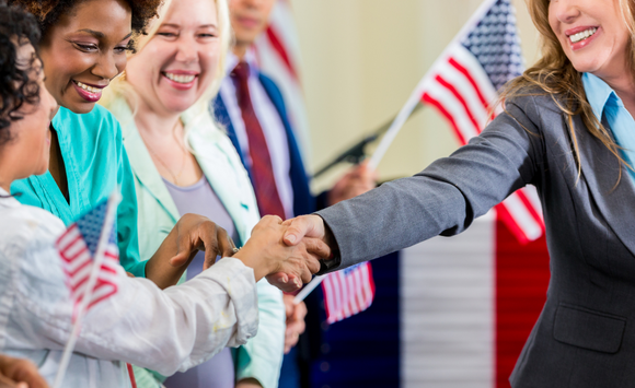 Cropped stock photo of a smiling person shaking hands with people in a crowd.