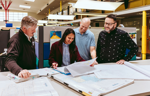 Photo of four Environmental Utilities engineers looking at a plan