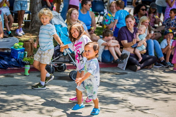 Two toddlers smiling and walking on a path during the Story Stroll Fun Run